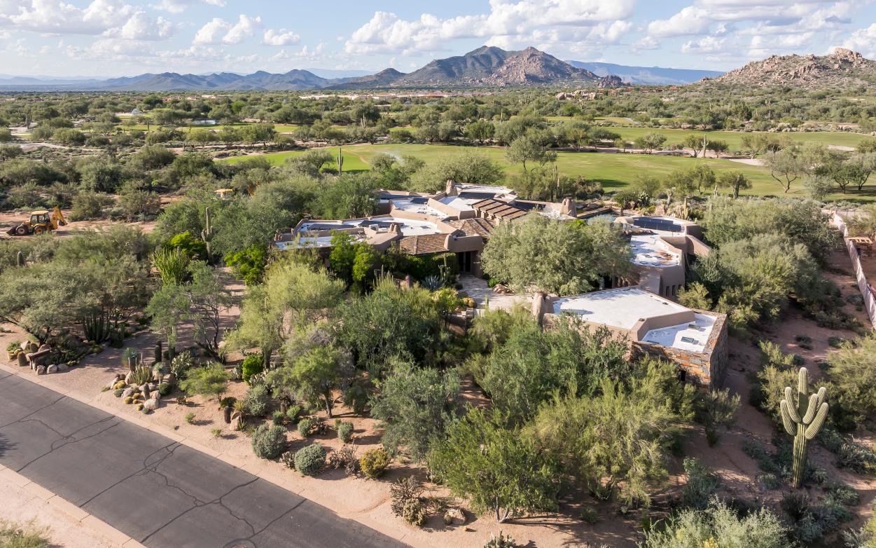An elevated view of the residence amid desert vegetation and distant mountains.