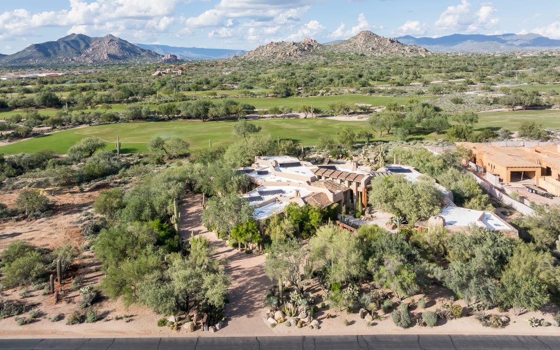 The residence, neighboring homes and golf-course landscape beneath a mountain horizon.