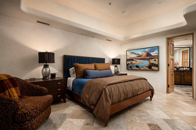 A bedroom with natural stone flooring and a softly illuminated ceiling.