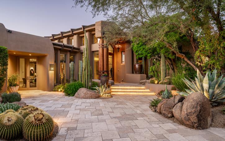 Stone paving, sculptural cacti and warm light frame the entry courtyard.