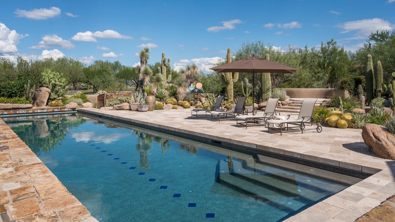 The lap pool reflects the sky beside stone terraces and desert plantings.