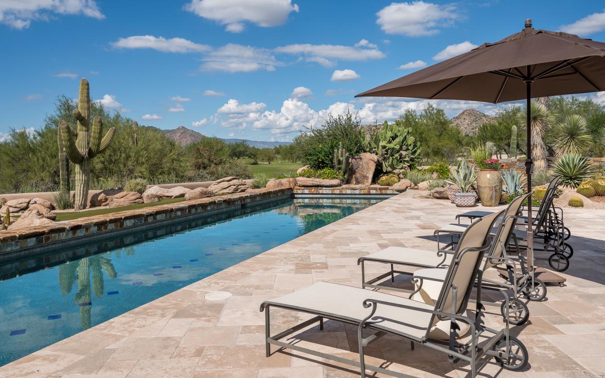 Lounge chairs line the pool terrace against a desert and mountain backdrop.