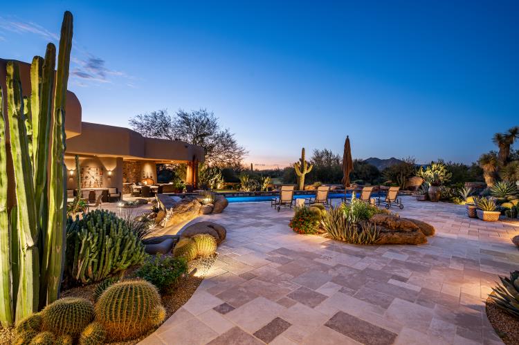 Illuminated desert planting and broad stone terraces beside the pool.
